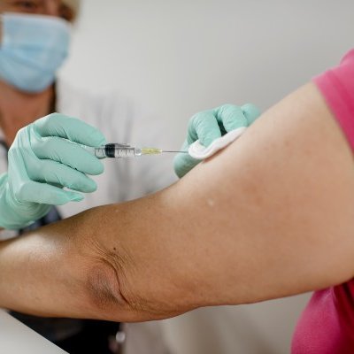 Vaccine being injected into older woman's arm.